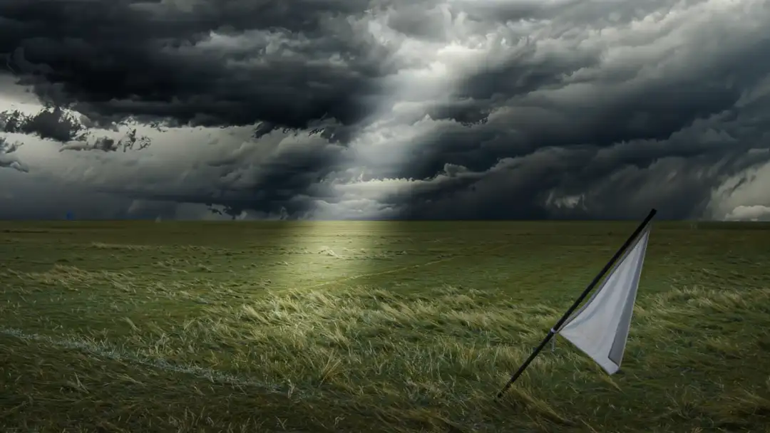 Corner flag bending in stormy wind with a shaft of light on the grass