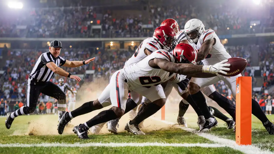 Runner stretching the ball toward the pylon on fourth-and-one as lines collide