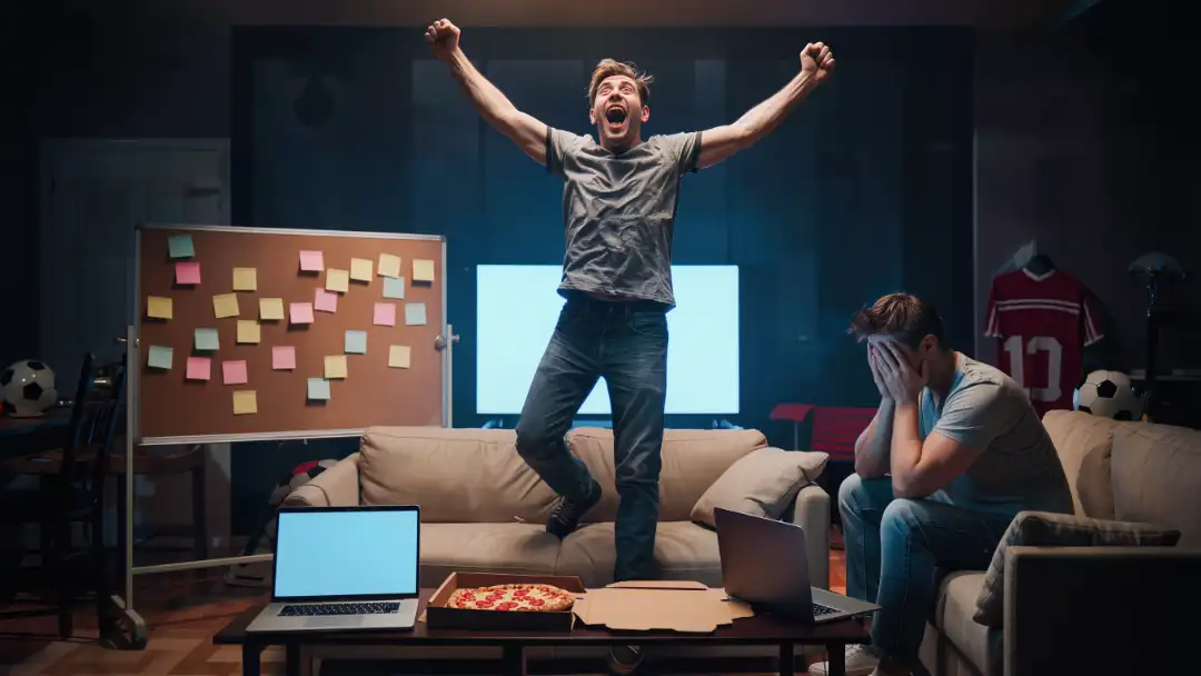 One friend celebrating a fantasy pick while another buries his face in his hands