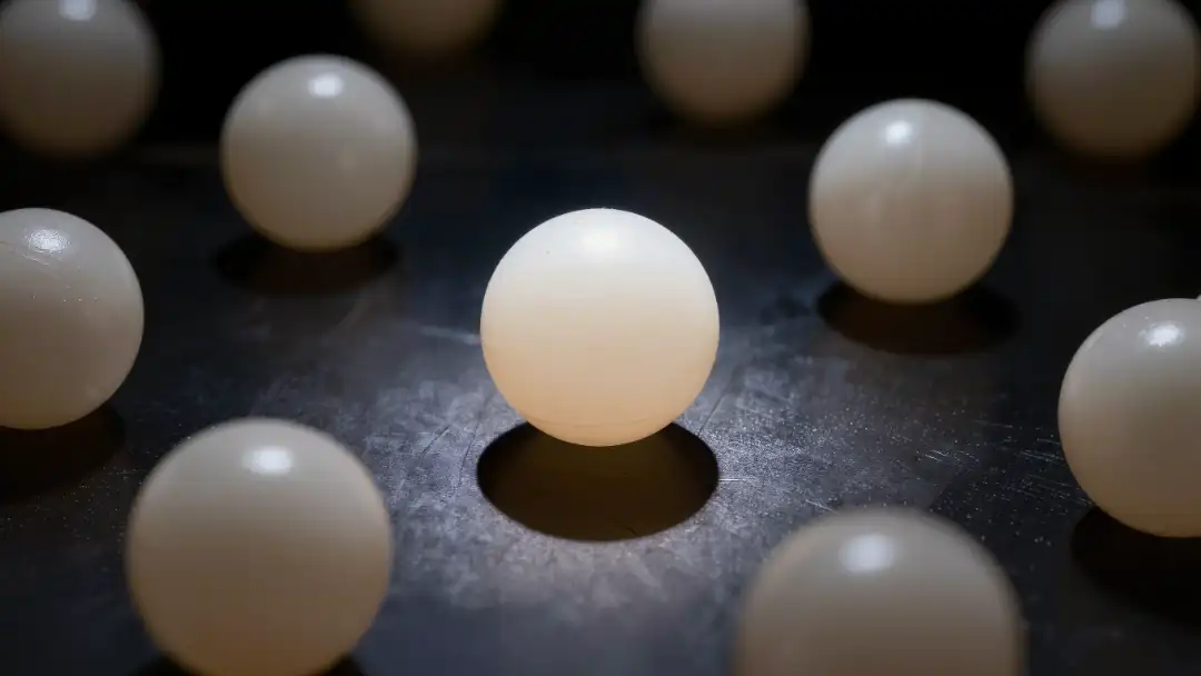 Macro shot of white ping pong balls on a dark reflective surface
