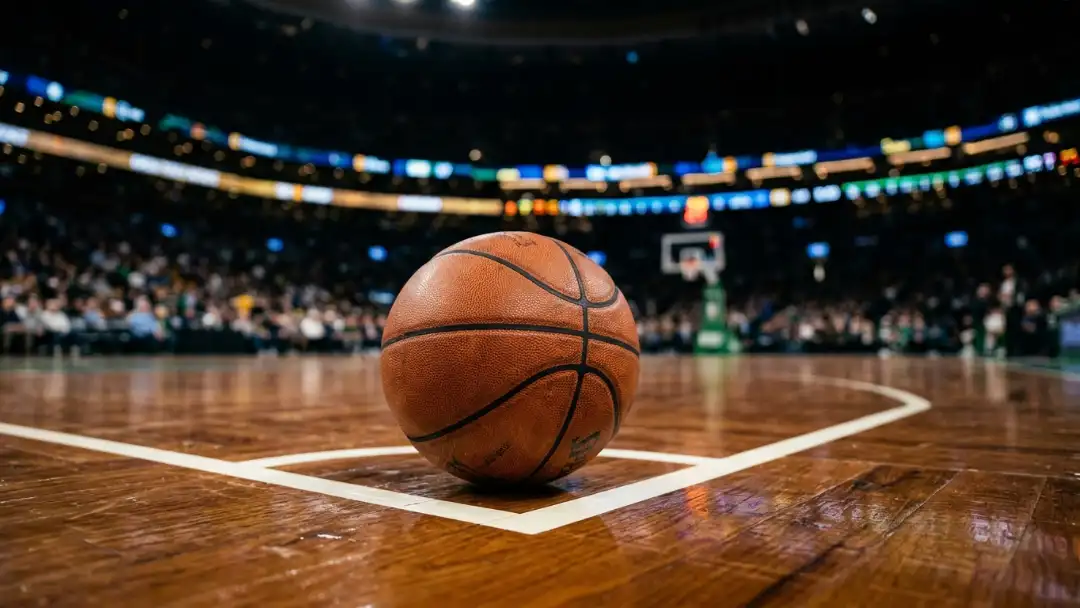 Basketball resting on hardwood behind the three-point line