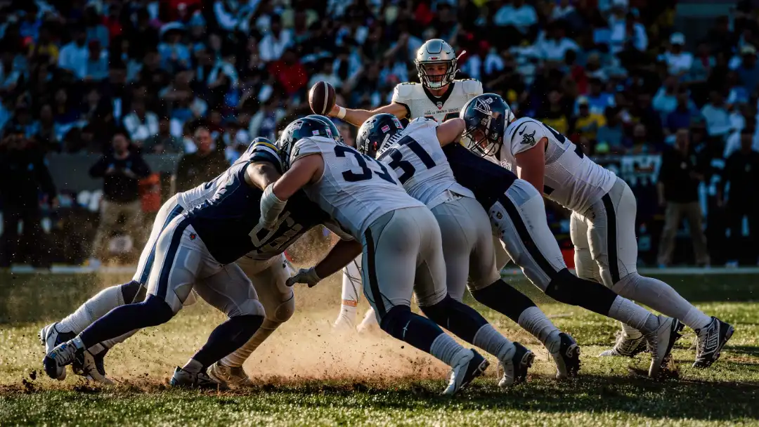 Offensive and defensive linemen colliding at the snap in front of a packed crowd