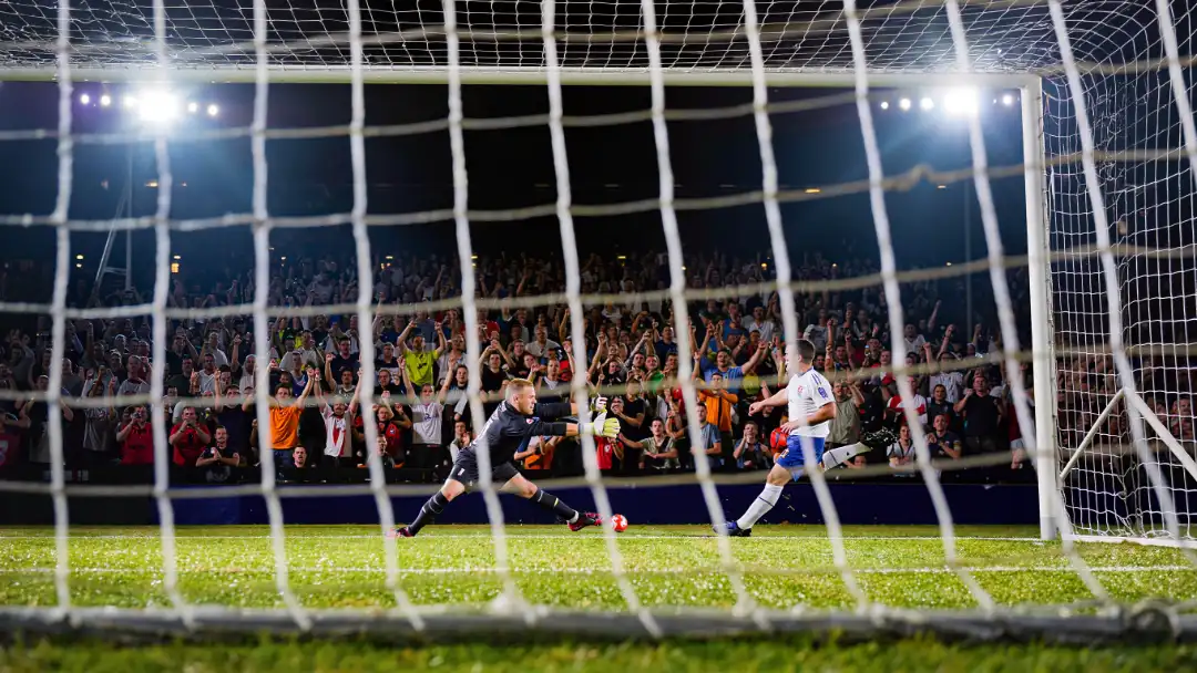 penalty shootout seen from behind the goal net at night