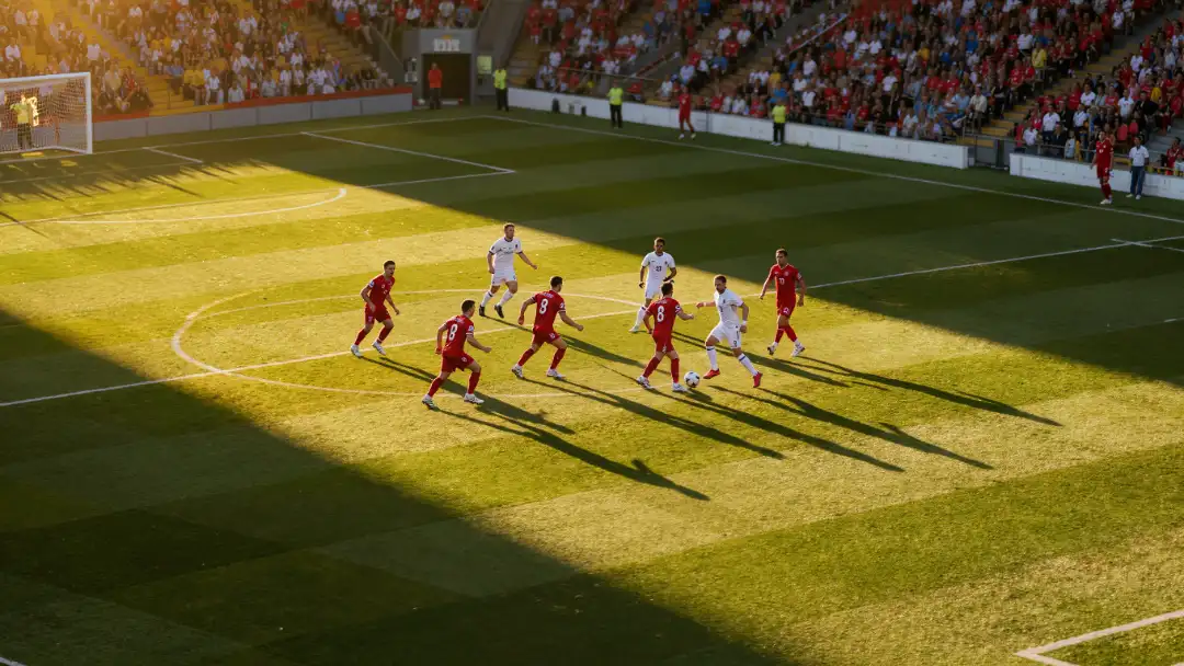 Team in red knitting a possession triangle in midfield under late afternoon sun
