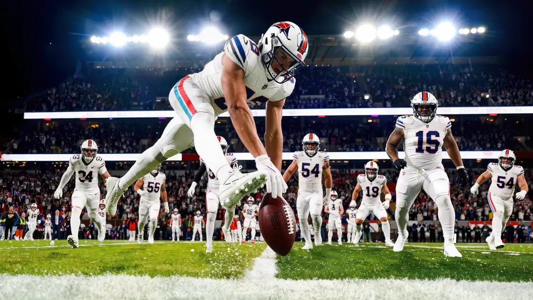 Tight end spiking the football in the end zone as teammates rush in