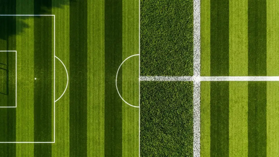 White pitch lines intersecting on green grass, viewed from above
