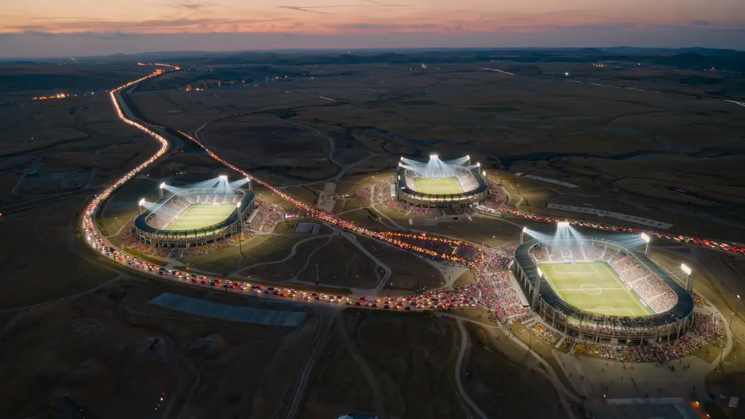 Aerial dusk view of three glowing host stadiums connected by streams of light during the 2026 World Cup